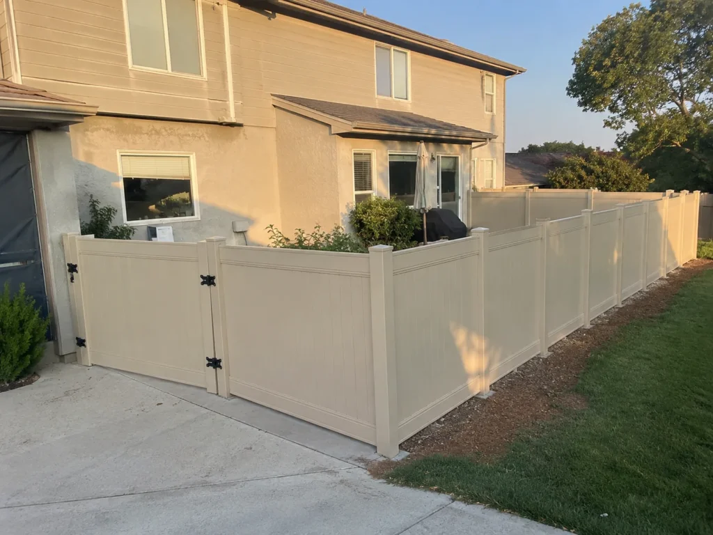 tan vinyl privacy fence and gate along a house shown at a property in Cedar Rapids, Iowa